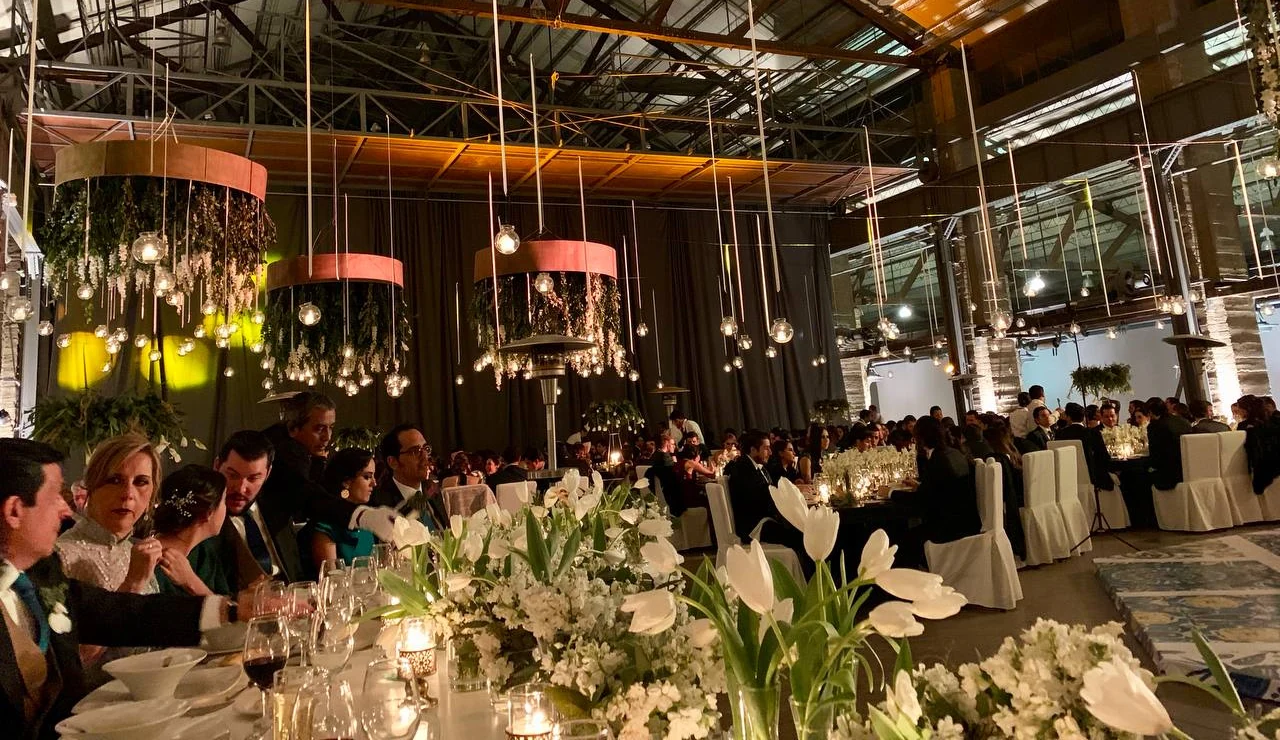Guests seated at flower-lined tables beneath hanging lights