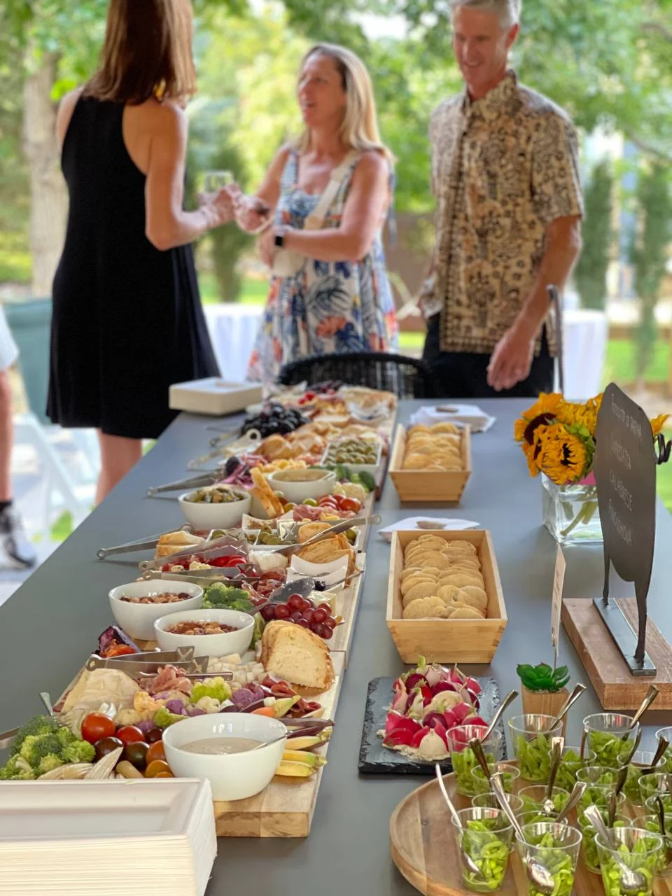 Grazing table with cheeses, vegetables, dips and appetizers, with guests gathered behind it